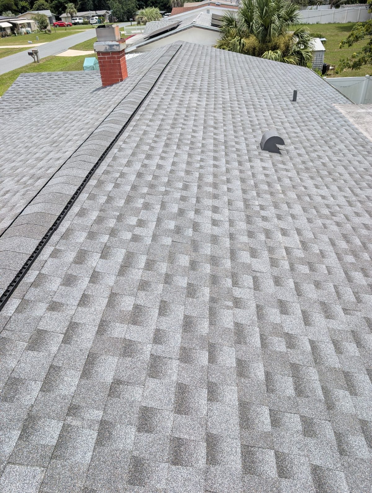 Finished gray shingle roof with new ridge vent
